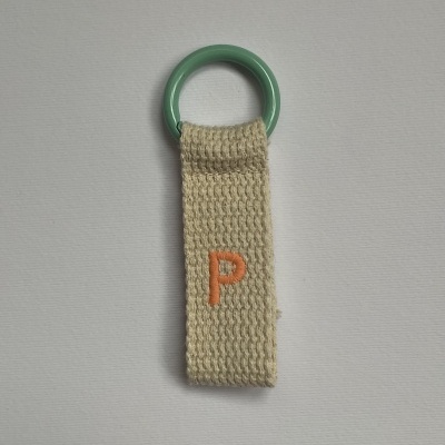 Chaveiro com argola verde e fita bege com letra P em laranja