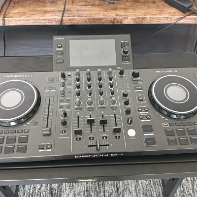 Consola DJ Denon DJ SC LIVE 4 com ecrã e botões sobre mesa preta.