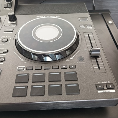 Equipamento de DJ preto com disco giratório e múltiplos botões de controlo