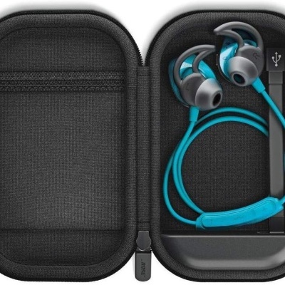 Estojo preto aberto com auriculares azuis e cinzentos, cabo USB preto e base de carregamento preta