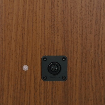 Tomada preta com conector e adesivo SIGN 50 numa superfície de madeira