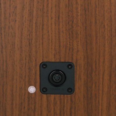 Entrada de conector circular preta num painel de madeira castanha com autocolante QC 05