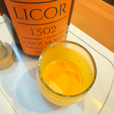 Garrafa de licor laranja e copo com líquido amarelo