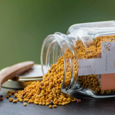 Frasco de vidro com pó amarelo alaranjado e colher de madeira