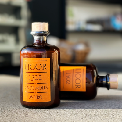 Frascos de licor âmbar com rótulo laranja e tampa de cortiça.