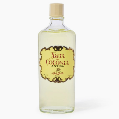 Frasco de água de colónia antiga transparente com rótulo amarelado e tampa bege