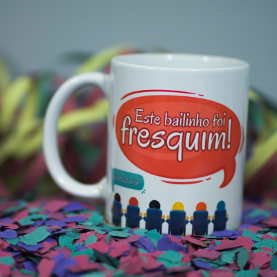 Caneca branca com texto 'Este bailinho foi fresquim!' e confetes coloridos à volta