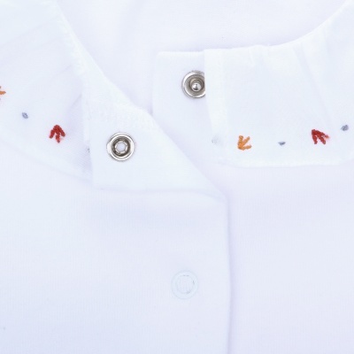Peça de vestuário branca com botão de pressão e bordados coloridos na gola