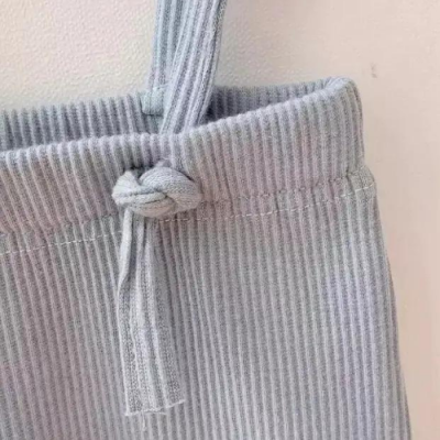 Pormenor de peça de roupa cinzenta riscada com cordão amarrado