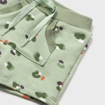 Calças de criança verdes claras com padrão de manchas coloridas e cós elástico com cordão.