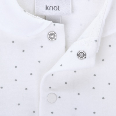 Roupa branca com pequenos pontos cinza e botões metálicos