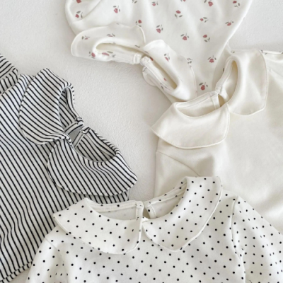 Bodies de bebé com colarinhos e diferentes padrões, dispostos sobre fundo branco