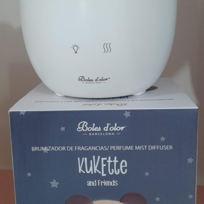 Difusor de fragrâncias em forma de coala branco e castanho em cima de embalagem azul