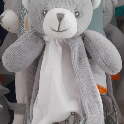 Boneco de peluche cinza e branco com etiqueta Baby Nat Bio pendurado em gancho