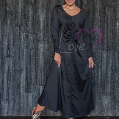 Mulher com vestido longo preto e botas prateadas em fundo cinzento