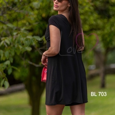 Mulher de costas usando vestido preto curto e óculos de sol, segurando bolsa vermelha