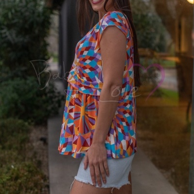 Blusa feminina colorida geométrica de manga curta com calções brancos ao ar livre