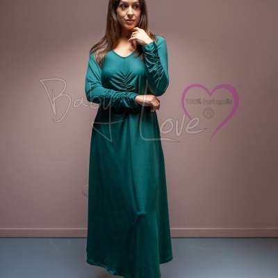 Mulher com vestido comprido verde de manga comprida em fundo interior rosa