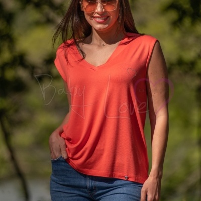 Mulher com túnica laranja e jeans azul ao ar livre