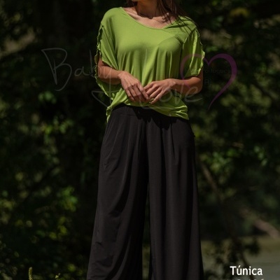 Mulher com túnica verde e pantalona preta ao ar livre