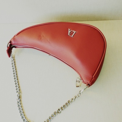 Mala de mão vermelha com alça de corrente prateada sobre fundo claro