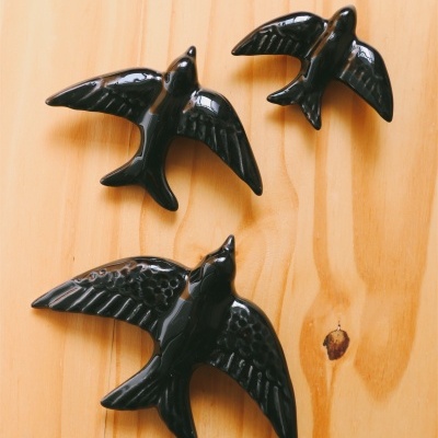 Figuras decorativas de pássaros pretos em superfície de madeira clara