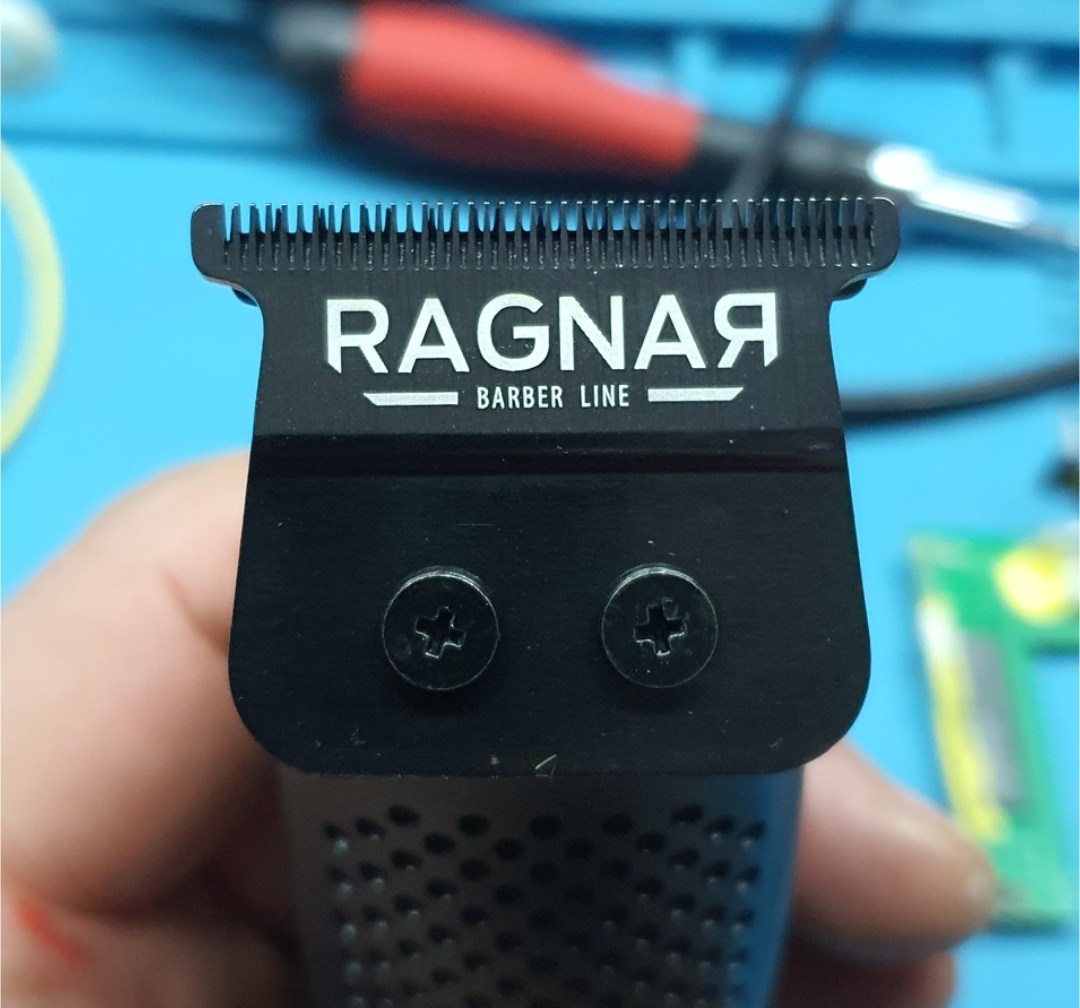 Máquina de cortar cabelo preta com lâmina metálica e texto RAGNAR BARBER LINE