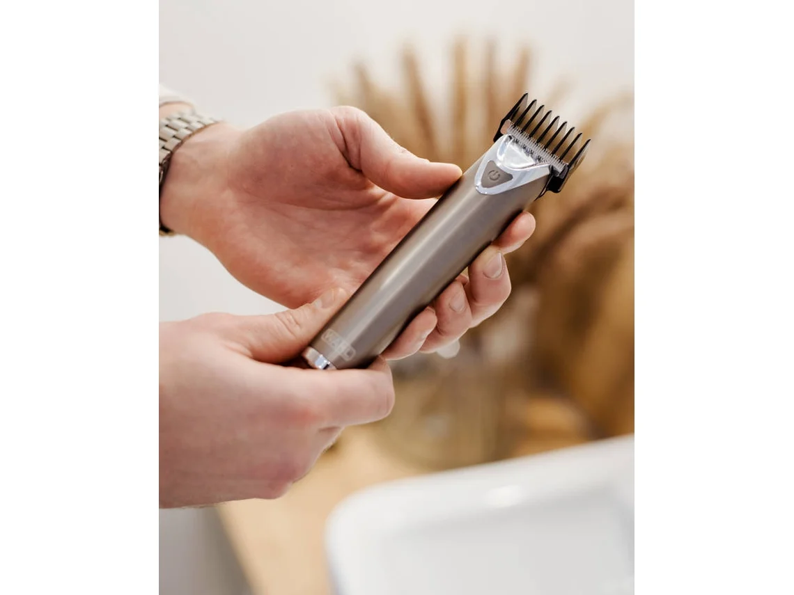 Máquina de corte de cabelo cinzenta nas mãos