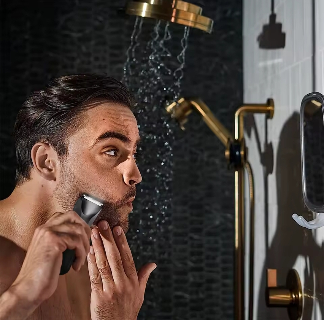 Homem a barbear-se com aparador elétrico em casa de banho com torneiras douradas e azulejos pretos