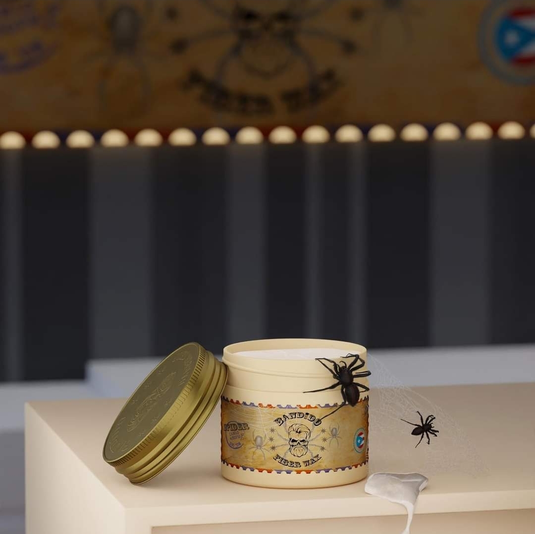 Vela branca em frasco com tampa dourada e etiqueta decorativa de aranhas