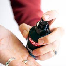 Mão a pulverizar produto de garrafa preta com texto 'UPPERCUT'