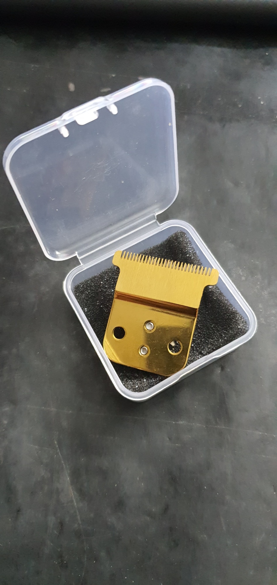 Lâmina dourada para máquina de barbear numa caixa transparente com espuma preta