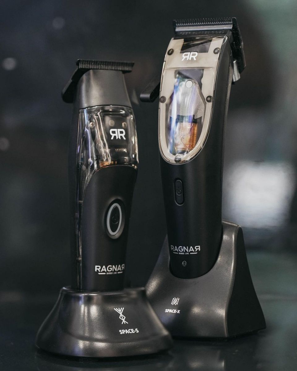 Duas máquinas de cortar cabelo pretas em suportes de carregamento com marcas RAGNAR e SPACE X