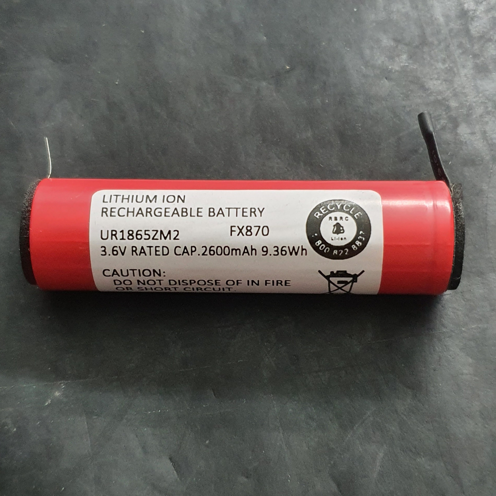 pilha recarregável de íon de lítio vermelha com etiqueta branca num fundo negro