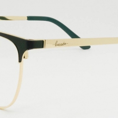 Óculos dourados com hastes verdes em fundo branco