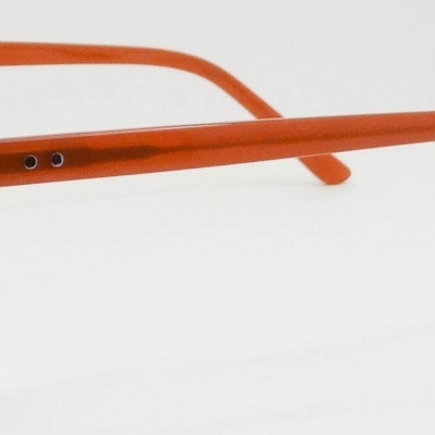 Óculos de armação plástica laranja com lentes transparentes e detalhes metálicos