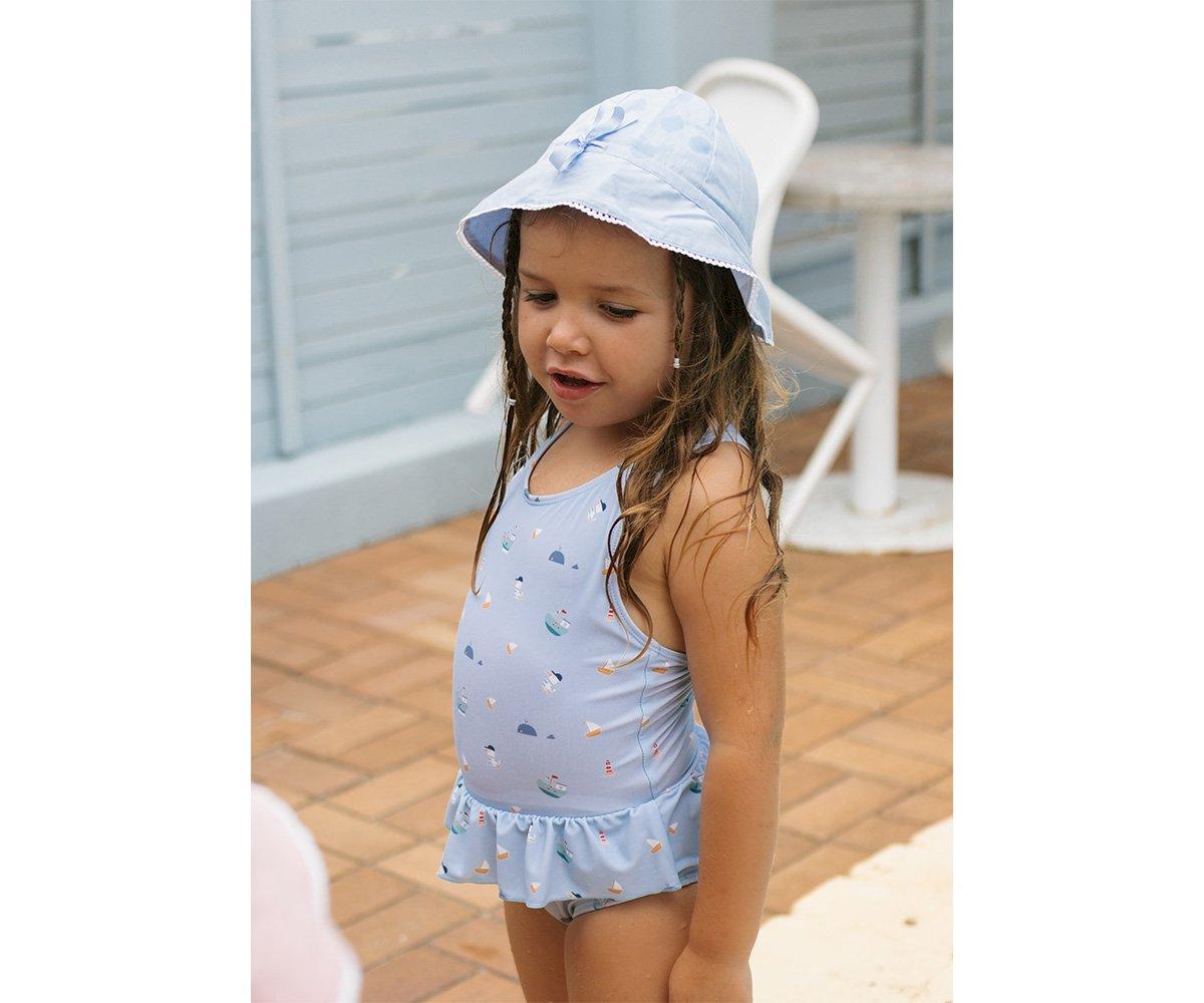 Menina com fato de banho azul claro e chapéu azul