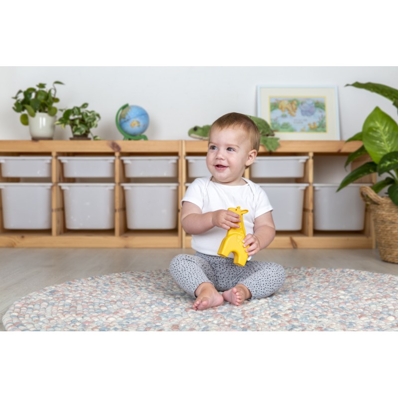 Bebé sentado num tapete colorido segurando um brinquedo amarelo de girafa