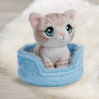 Pelúcia de gato bege e branco numa cama azul clara macia