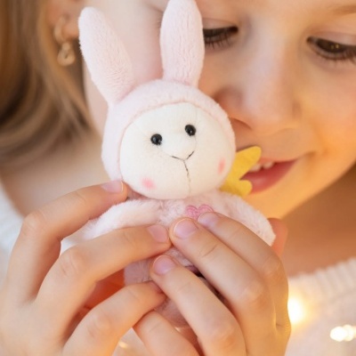 Menina a segurar um peluche cor-de-rosa com forma de coelho