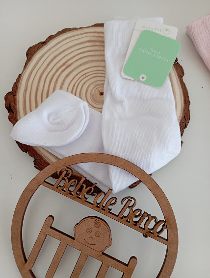 Meias brancas com etiqueta, círculo de madeira decorativo e recorte de madeira com texto