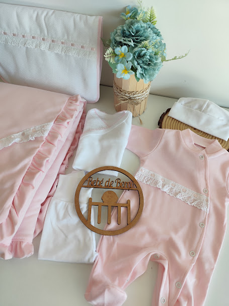 Roupas de bebé cor de rosa e branco com flores artificiais azuis e amarelas