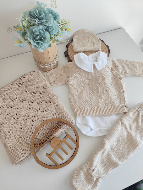 Conjunto de roupa de bebé bege com gola branca, manta bege e arranjo de flores azuis