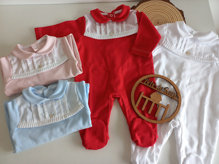 Babygrows coloridos para bebé com detalhes em branco e suporte decorativo de madeira