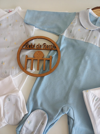 Macacões de bebé em branco e azul claro com padrão floral e emblema de madeira com texto