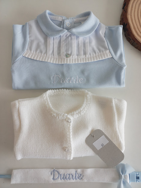 Roupa de bebé azul e branca com nome Duarte bordado e faixa com fita azul
