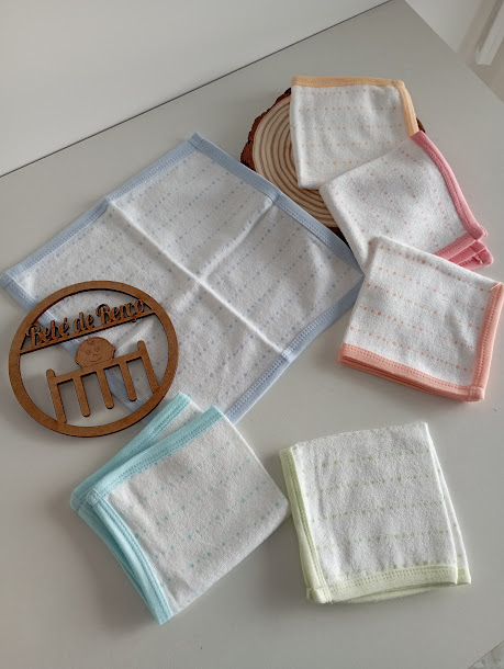 Conjunto de toalhas coloridas com padrões de pontos ao lado de uma placa de madeira