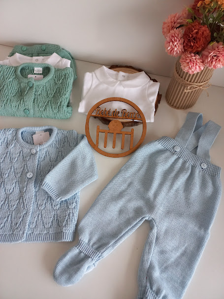 Conjunto de roupa de bebé em malha azul e verde com decoração de flores e ornamento de madeira