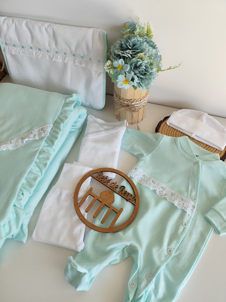 Conjunto de roupas de bebé verde-água e branco com renda, manta e arranjo floral azul e verde