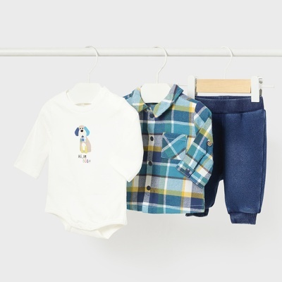 Conjunto de bebé com body branco com desenho de cão, camisa xadrez azul e calças azul-escuro pendurado em cabides.